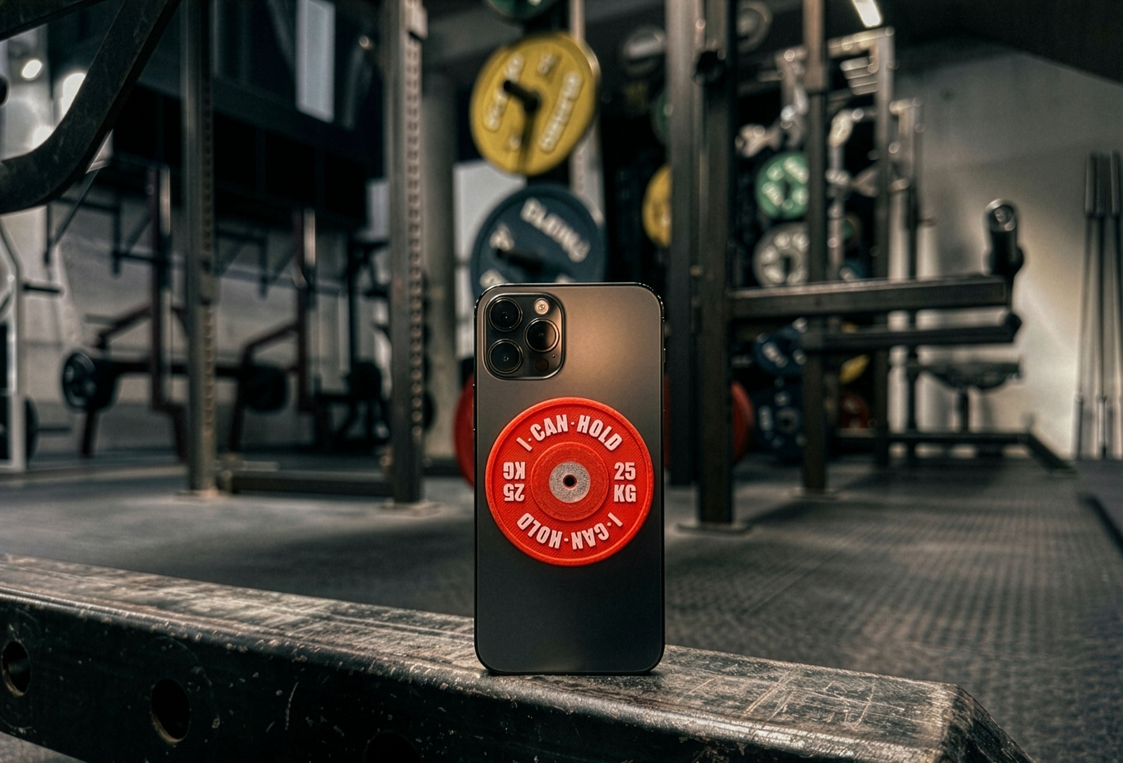 I•CAN•HOLD 25kg Red Edition montiert an einem Smartphone in einem Oldschool Powerlifting Gym aufgestellt auf einem Powerrack