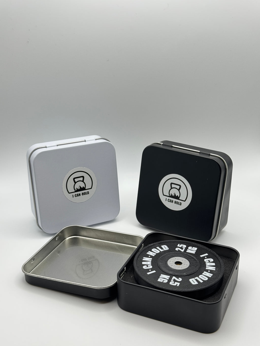 I•CAN•HOLD 2,5kg Black Edition, die MagSafe Handyhalterung für's Gym drapiert mit drei metallischen Aufbewahrungsboxen in weiß und schwarz