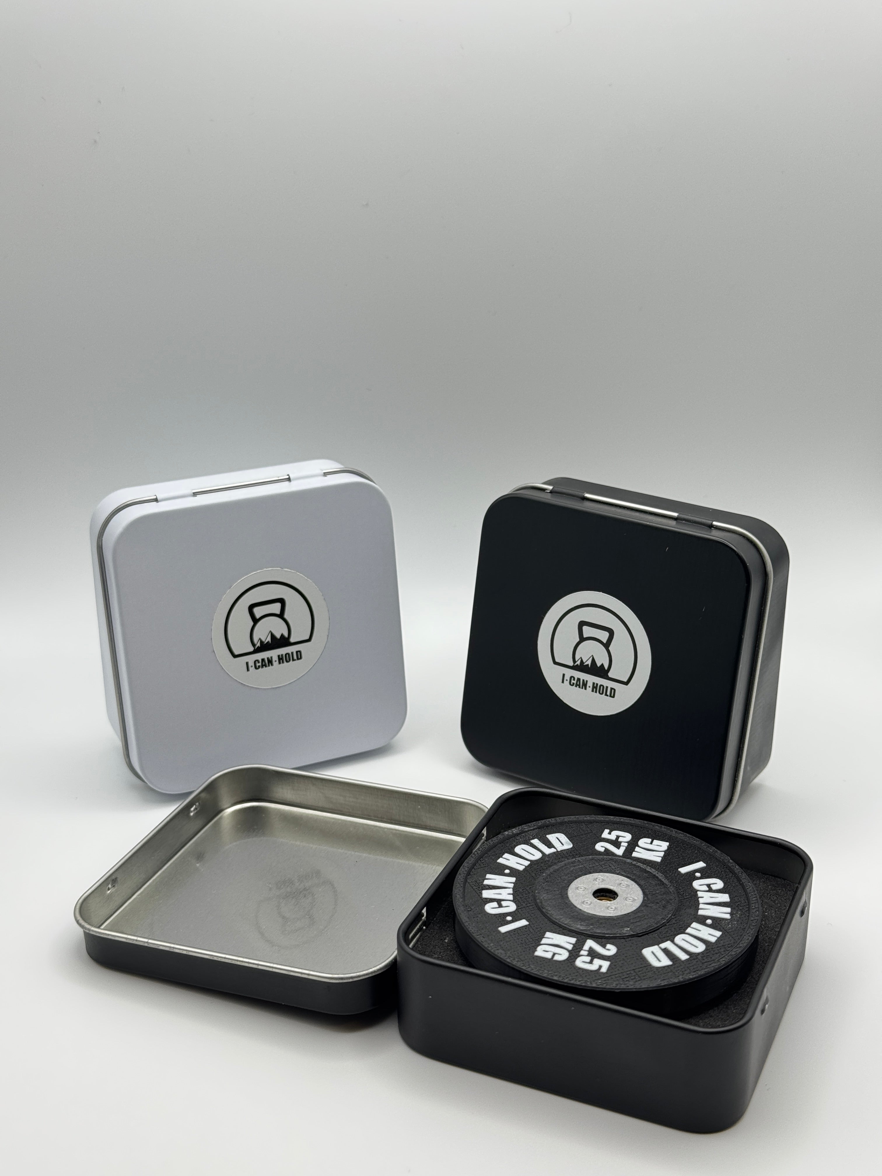 I•CAN•HOLD 2,5kg Black Edition, die MagSafe Handyhalterung für's Gym drapiert mit drei metallischen Aufbewahrungsboxen in weiß und schwarz