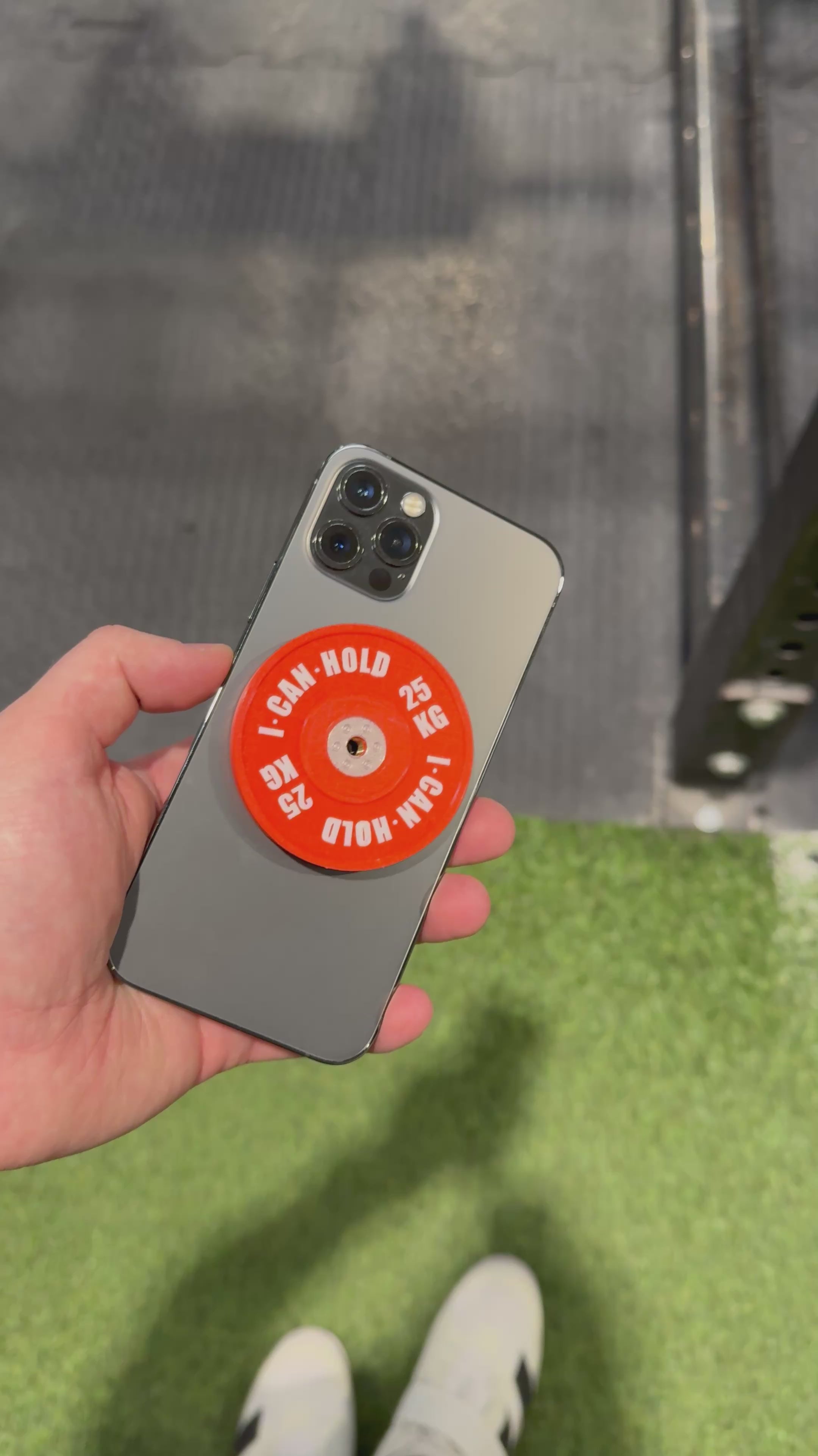 Ein rotes I CAN HOLD ist auf einem iPhone montiert und es wird demonstriert, wie diese Kombination auf einem Fitnessgerät montiert wird